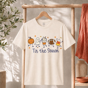 Cute Halloween Pumpkin Ghost Football Coffee Candy Corn Shirt displayed on hanger, featuring colorful cartoon designs.