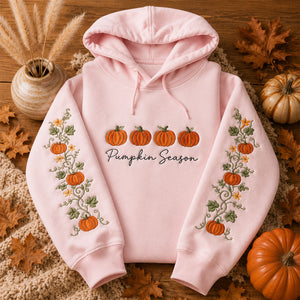 Pumpkin Season Embroidered Hoodie displayed with autumn leaves and pumpkins on a wooden table.