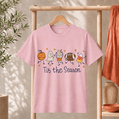 Cute Halloween Pumpkin Ghost Football Coffee Candy Corn Shirt on a pink t-shirt with playful graphics and text 'Tis the Season.