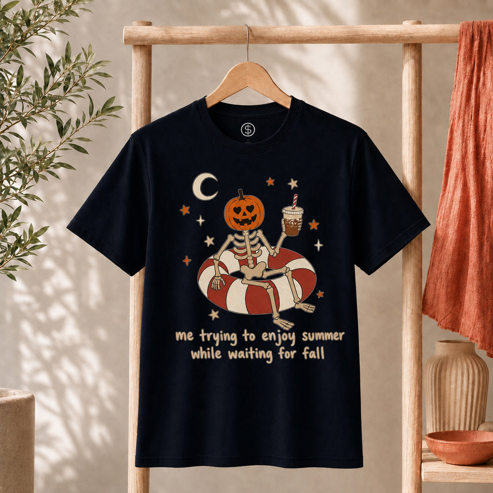 Me Trying to Enjoy Summer While Waiting for Fall Tee featuring skeleton with jack-o'-lantern on a pool float holding iced coffee.