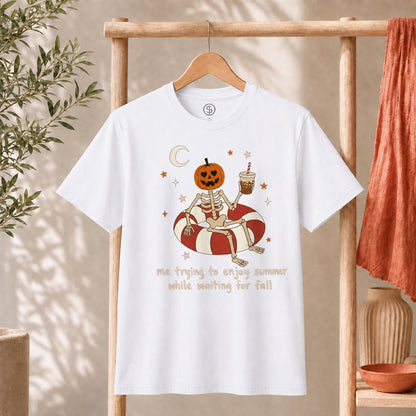 Me Trying to Enjoy Summer While Waiting for Fall Tee featuring a skeleton with a jack-o'-lantern head on a pool float.