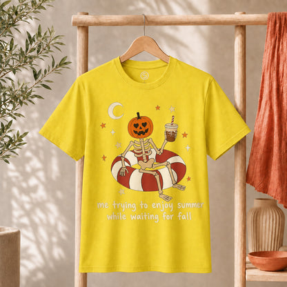 Me Trying to Enjoy Summer While Waiting for Fall Tee featuring a skeleton with a jack-o'-lantern head on a float.