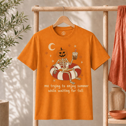 Me Trying to Enjoy Summer While Waiting for Fall Tee featuring a skeleton with a jack-o'-lantern, iced coffee, and crescent moon.